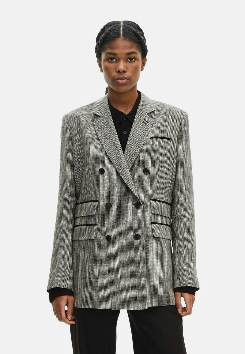Doppelt breiter Blazer aus grauem Hahnentrittmusterstoff, mit schwarzen Knöpfen, seitlichen Taschen und Spitzenrevers. Strukturierter, taillierter Schnitt.