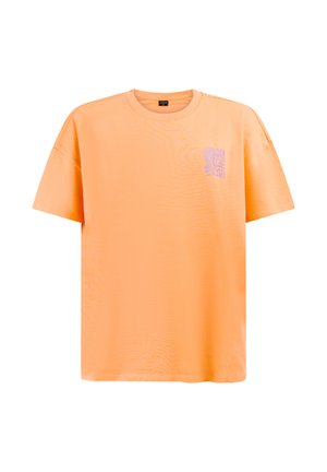 Narančasta majica kratkih rukava s okruglim izrezom i malom ljubičastom apstraktnom grafikom na gornjem lijevom dijelu prsa.