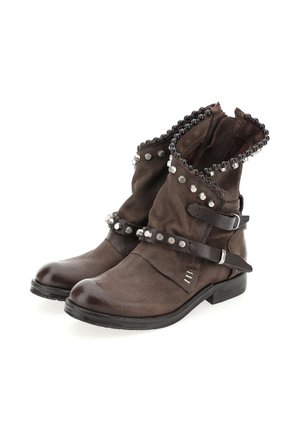 Bruine leren enkelboots met zwarte kralen en zilveren studs, met banden en gespen op een witte achtergrond.