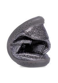 Zapato de charol negro y plateado con material suave y flexible, forma redondeada y suela perforada gris. Detalles de acabado metálico brillante.