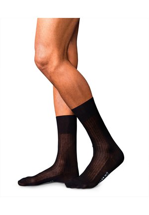Calcetines negros con un diseño acanalado y una sección superior semi-translúcida, que cuentan con un puño sólido y una zona de puntera reforzada.