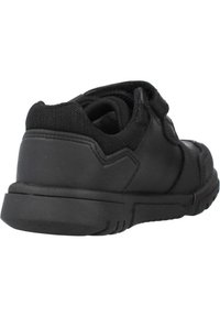 Chaussure de sport noire avec une tige synthétique lisse, un col rembourré, une sangle Velcro et une semelle en caoutchouc texturée pour une meilleure adhérence.