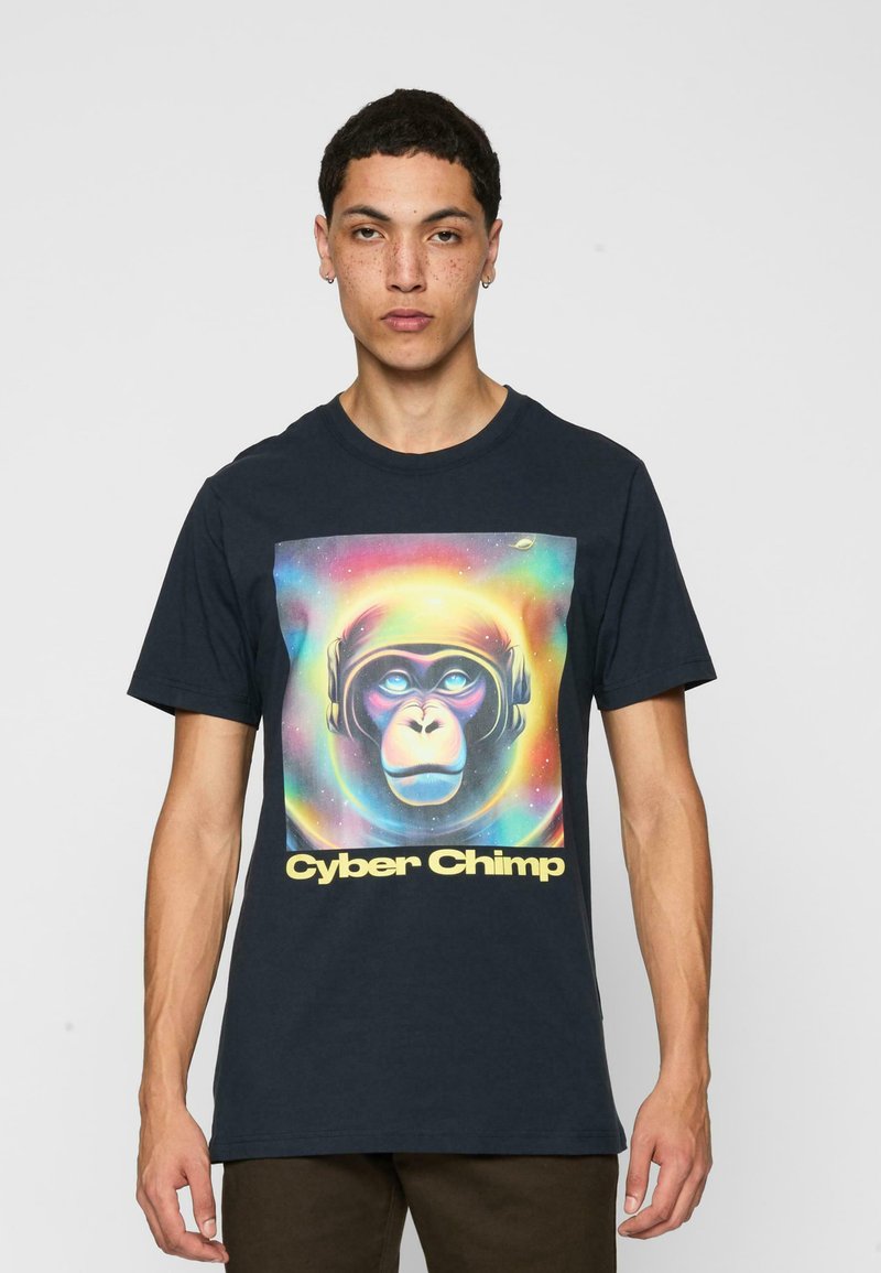Tumši zila kokvilnas T-krekls ar krāsainu grafiku, kurā attēlots pērtiķis ar austiņām un uzraksts "Cyber Chimp" dzeltenā krāsā. Īsas piedurknes, standarta piegriezums.