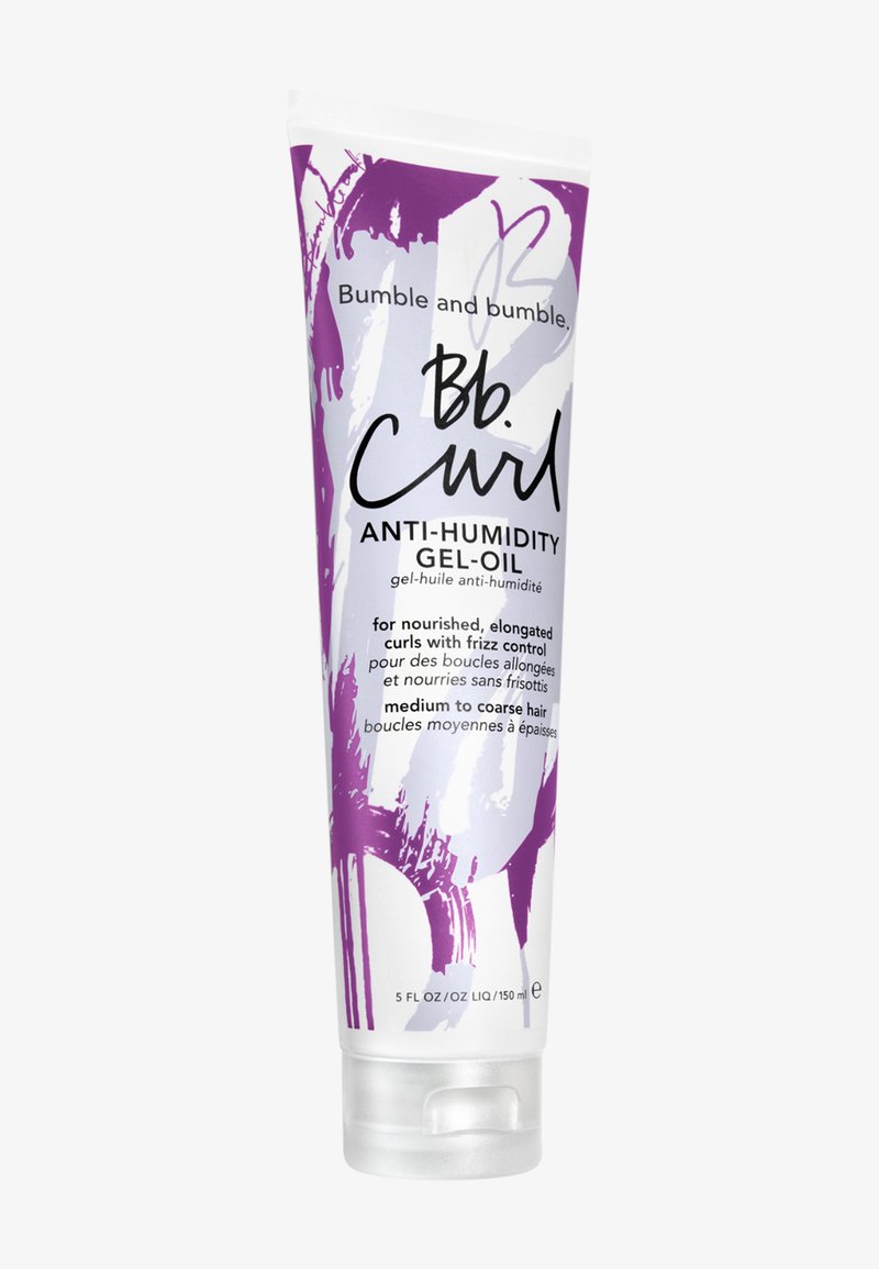 Produit capillaire bouclés dans un tube en plastique transparent et flexible ; blanc avec un design abstrait violet, comporte un texte noir et un capuchon à rabat.