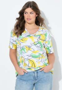 T-shirt a maniche corte con scollo a V in cotone bianco con motivi astratti a linee gialle e verdi. Caratterizzato da una vestibilità rilassata e orlo curvo.