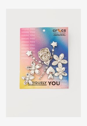 Breloques Crocs Jibbitz en argent en forme de fleurs, d'étoiles, d'une rose et de cœurs sur un fond de carte dégradé coloré.