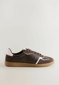 Sneaker marroni con accenti rosa, caratterizzati da un design a profilo basso, con lacci e suola in gomma testurizzata, su uno sfondo chiaro.