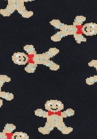 Tkanie dziane z powtarzającymi się wzorami piernikowych ludzików w beżu z jasnoniebieskimi akcentami i czerwonymi muszkami na ciemnym granatowym tle.