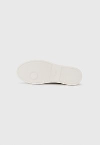 Semelle de chaussure en caoutchouc blanc avec un motif de grip texturé et un détail circulaire. Le nom de la marque "BOSS" est embossé près du talon.