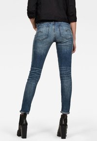 Smalblå denimjeans med en blekt tvätt, synliga sömnadsdetaljer och två bakfickor. Bärs med svarta högklackade ankelstövlar.