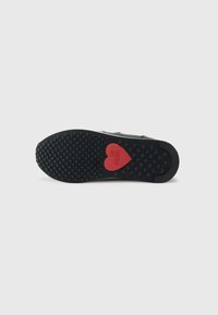 Zwarte rubberen schoenzool met een textuurpatroon voor grip; is voorzien van een rood hartaccent met het "LOVE MOSCHINO" logo.