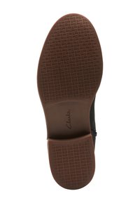 Semelle en caoutchouc marron d'une chaussure avec une surface texturée et à motifs. Le nom de la marque "Clarks" est embossé au centre.