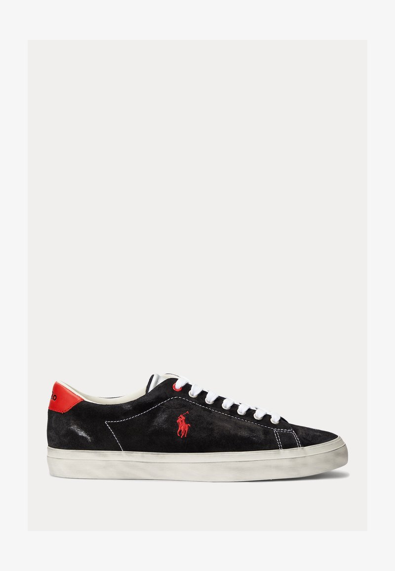Μαύρο σουέτ sneakers με λευκά κορδόνια, κόκκινες λεπτομέρειες στην φτέρνα και ένα μικρό κόκκινο λογότυπο. Διαθέτει επίπεδη, καουτσούκ σόλα και απλή ραφή.