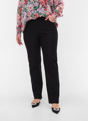 Black tailored pants with a straight leg, featuring a smooth texture. Paired with pointed black shoes adorned with a decorative gem.