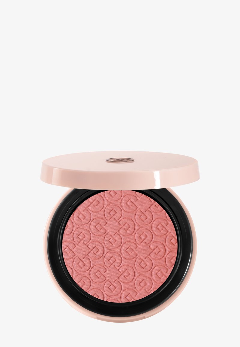 Poudre compacte dans un étui rose clair, avec un motif géométrique embossé sur la poudre corail-rose et un couvercle partiellement ouvert dévoilant un logo métallique.