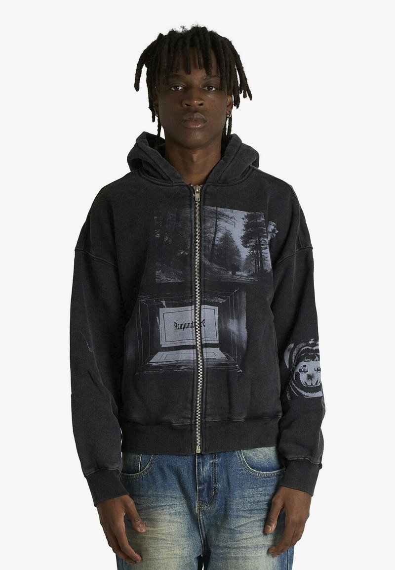 Felpa nera con zip e grafica frontale che raffigura alberi e una cornice con la parola "Recycund." Polsini e orlo a coste. Vestibilità casual.