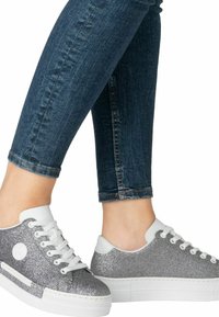 Baskets à paillettes argentées avec des accents blancs, bout rond et design à lacets. Associées à un jean bleu foncé bien ajusté qui met en valeur l'ourlet.
