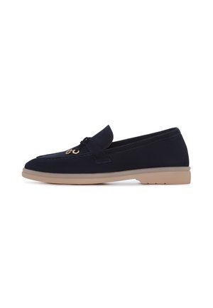 Marineblauwe nubucklederen loafer met een gladde textuur, voorzien van een strikaccent aan de voorkant en een lichtbruine rubberen zool. Klassiek instapontwerp.