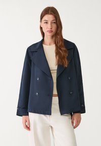 Námořnická modrá dvouřadá sako s širokými klopami a knoflíkovými detaily. Vyrobeno z hladké látky, s volným střihem a zkrácenou délkou.