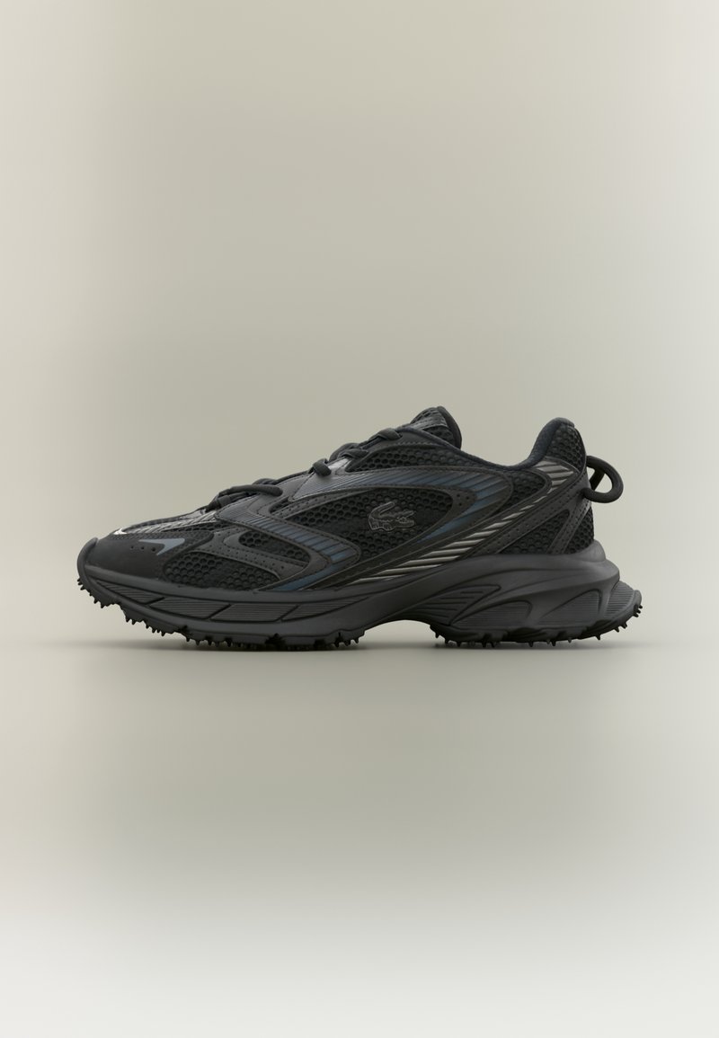 Baskets de sport noires avec panneaux en mesh et synthétiques, semelle texturée, logo latéral et languette au talon sur fond neutre.
