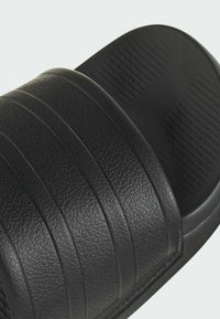 Black slide-on sandal with textured synthetic upper featuring three horizontal stripes, contoured footbed, and textured rubber sole for grip.