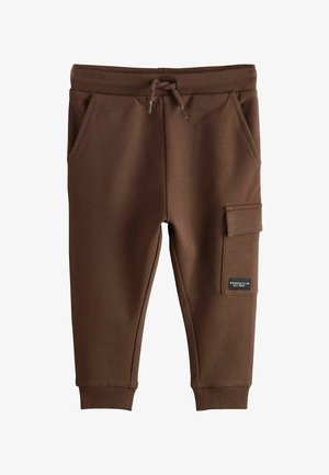 Brune børnejoggingbukser med elastisk talje, snøre, sidelommer, manchetter ved anklerne og en cargolomme med lap på højre ben.
