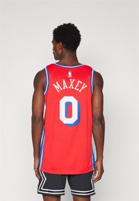 Maglietta da basket rossa con accenti blu, con scritto "MAXEY" e il numero "0" in bianco. Realizzata in tessuto a rete, con logo NBA sul retro.