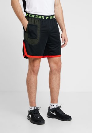 Sorte atletikshorts med røde accenter, en stor grøn lomme på venstre side og en grøn elastisk linning med teksten "NIKE SPORTS."