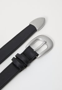 Schwarze Leder-gürtel mit silbernen Metall-schnallen; einer hat eine abgerundete spitze, während der andere eine rechteckige schnalle mit keeper-schlaufen hat.