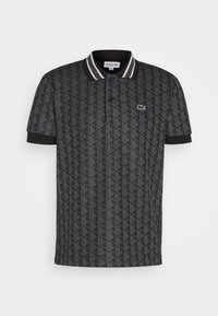 Polo noir avec motif géométrique gris, patte de boutonnage à deux boutons, col rayé et petit logo crocodile vert sur la poitrine.