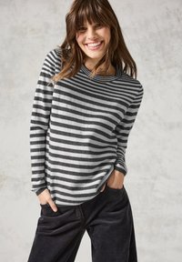 Grijze en witte gestreepte sweater, ronde halslijn, lange mouwen, gemaakt van zacht materiaal. Gecombineerd met donkere korduroypantalon.