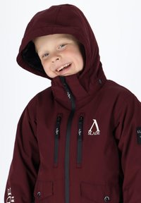 Giacca impermeabile bordeaux con cappuccio, dotata di logo e tasche con zip nere. Tessuto liscio, chiusure regolabili e polsini elasticizzati.