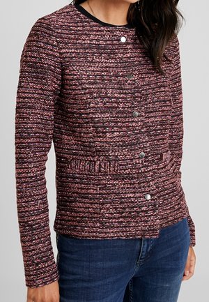 Veste en tweed texturé rose et violet avec des manches longues, un col rond et des boutons-pression argentés sur le devant. Présente un détail de taille froncé.