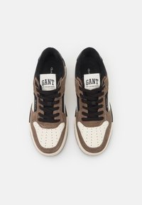 Braune Wildleder- und schwarze Stoff-Sneaker mit weißen Akzenten, perforierter Zehenkappe, schwarzen Schnürsenkeln und GANT-Logo auf der Zunge und der Seite.