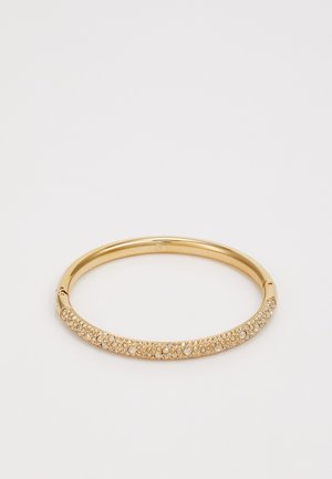 Złota, metaliczna bransoletka w formie bangle z gładką, błyszczącą powierzchnią, ozdobiona małymi, okrągłymi cyrkoniami po jednej stronie.