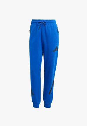 Blå atletiske sweatpants lavet af blødt stof, med en elastisk talje med snor og sorte sideakcenter samt logo.