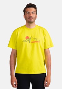 Žluté bavlněné tričko s ilustrací hor a slunce. "ROSSIGNOL" vytištěno červeně pod grafikou. Standardní střih s krátkým rukávem.