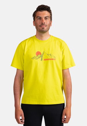Gelbes Baumwoll-T-Shirt mit Bergillustration und Sonne. "ROSSIGNOL" in Rot unter dem Grafikdruck. Standardpassform mit kurzen Ärmeln.