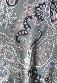 Tkanina w jasnym zielonym kolorze z misternymi wzorami kwiatowymi i paisley w kolorach granatowym, białym i delikatnym różowym, cechująca się finezyjnymi detalami i gładką teksturą.