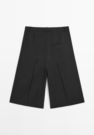 Shorts noirs à jambes larges en tissu léger. Caractérisés par une ceinture structurée, une poche arrière unique, une texture lisse et un design épuré.