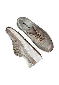 Beige sneakers met een textuur bovenkant, vetersluiting, subtiele metallic accenten en een dikke witte zool met een bruine loopvlak.