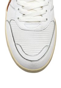 Zapatilla blanca con parte superior de cuero perforado, cordones blancos planos, acentos plateados y suela de goma texturizada. Superficie suave con costuras sutiles.