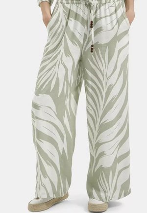 Szerokie spodnie z jasnym zielonym i białym wzorem liści, elastycznym pasem, sznurkiem z drewnianymi koralikami, noszone z białymi espadrylami.