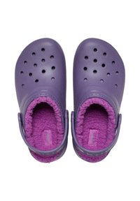 Sabots violets avec un intérieur doux et duveteux. Possède des perforations sur la coque extérieure et une sangle à l'arrière pour un maintien sécurisé.