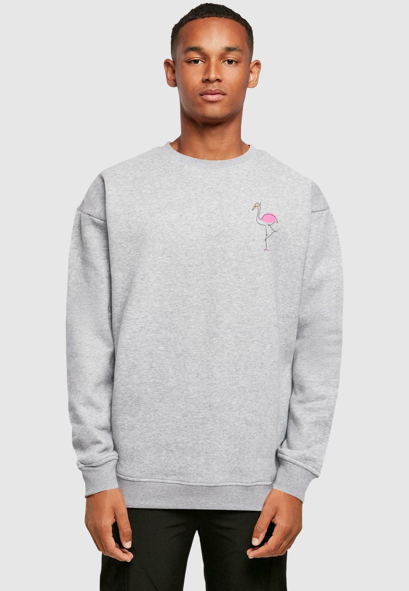 Sivý sweatshirt s dlhými rukávmi. Obsahuje malú grafiku ružovej plameniaka na hrudi. Mäkká štruktúra s rebrovanými manžetami a lemom.