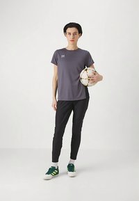 Gray athletic t-shirt, black fitted pants, green and white sneakers, and a multi-colored soccer ball held in hand. Simple design, lightweight fabric.