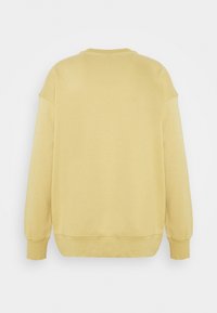 Żółta, miękka bawełniana bluza z okrągłym dekoltem, opuszczanymi ramionami oraz ściągaczami na mankietach i dole. Prosty design, bez widocznych logo czy wzorów.