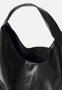 Černá kožená taška přes rameno s hladkým povrchem, širokým ramenním popruhem a prostorným interiérem s vnitřní kapsou na cvok.