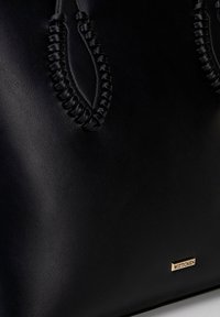 Borsa a tracolla in pelle nera con manici intrecciati e logo "WITTCHEN" in tonalità oro. La superficie è liscia con una finitura opaca.