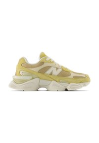 Baskets New Balance jaune clair et beige avec panneaux en mesh, semelle épaisse et lacets blancs, vues de côté.